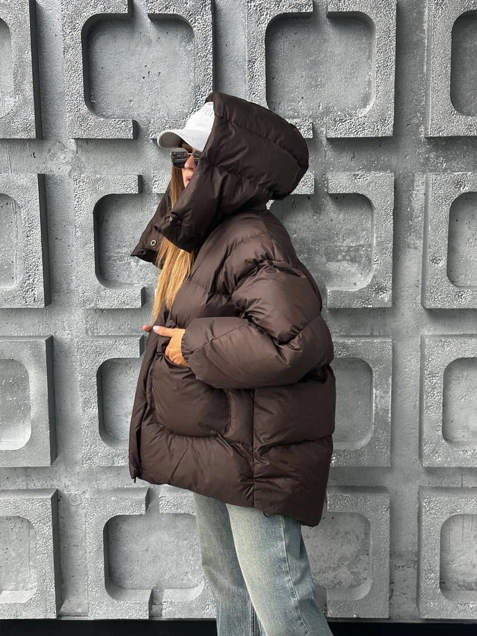 Dark brown hooded puffer with cap and pale jeans