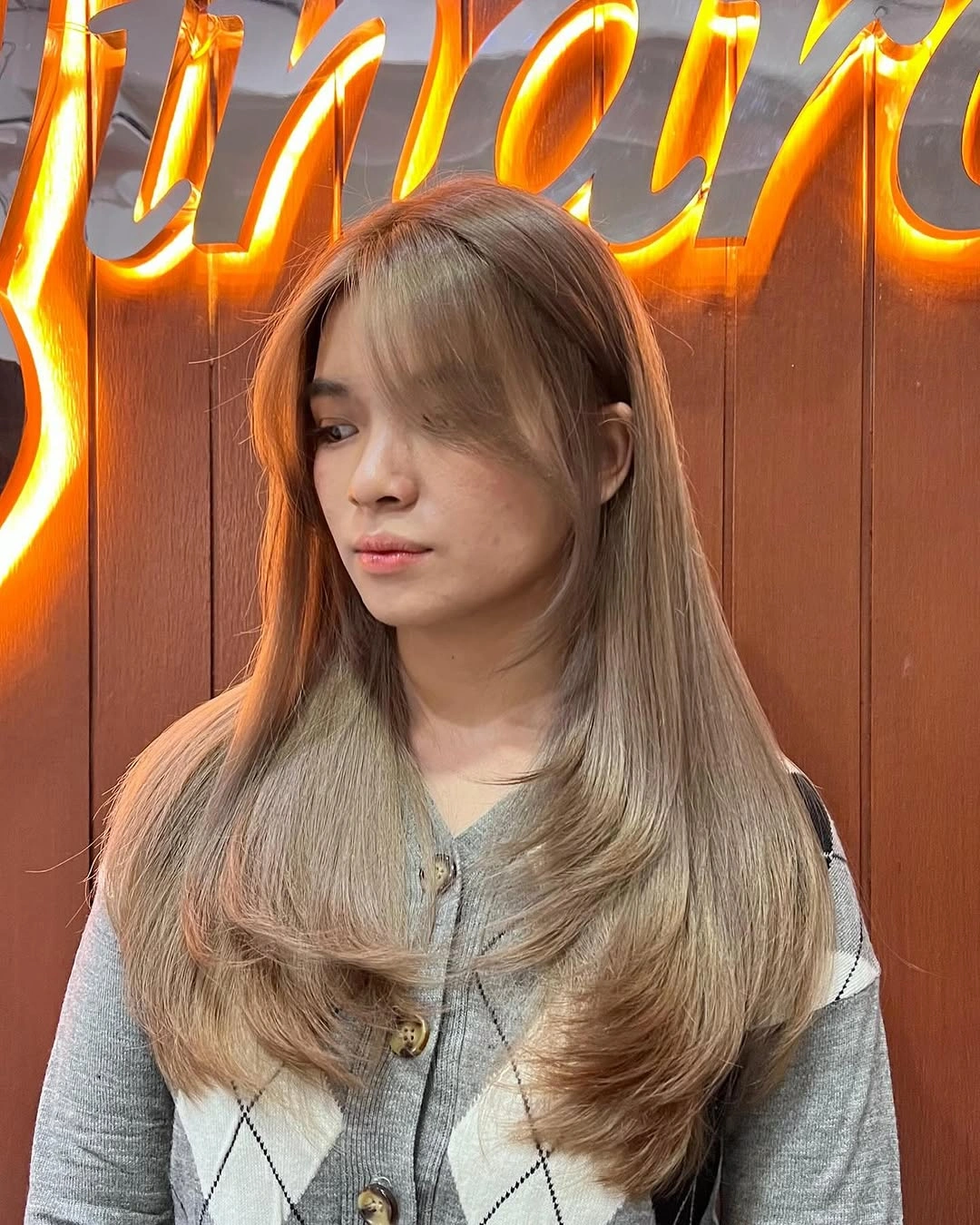 Long ash-blonde layers with sweeping curtain bangs and rounded ends
