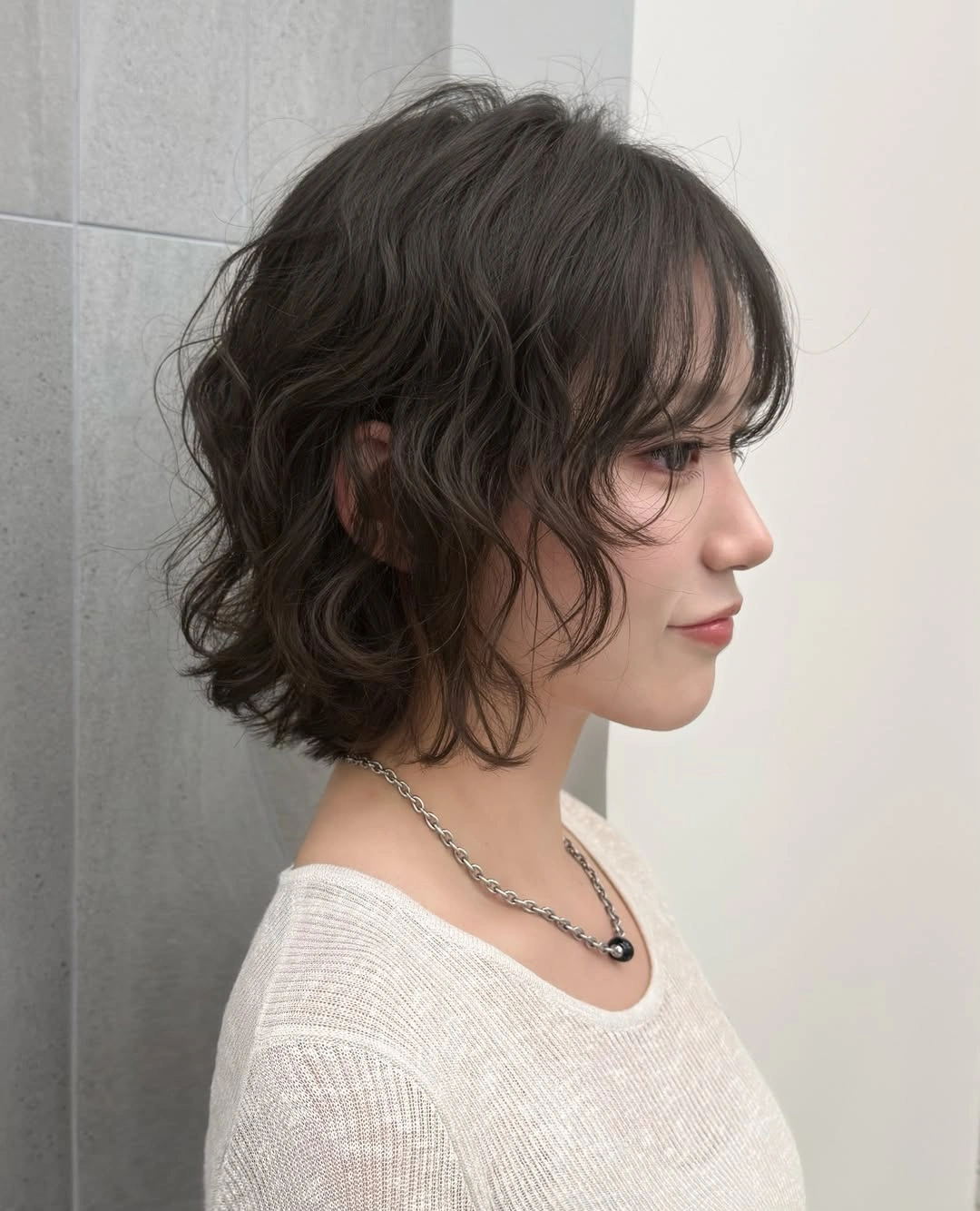 Wavy shoulder-length dark hair with soft fringe and layered ends