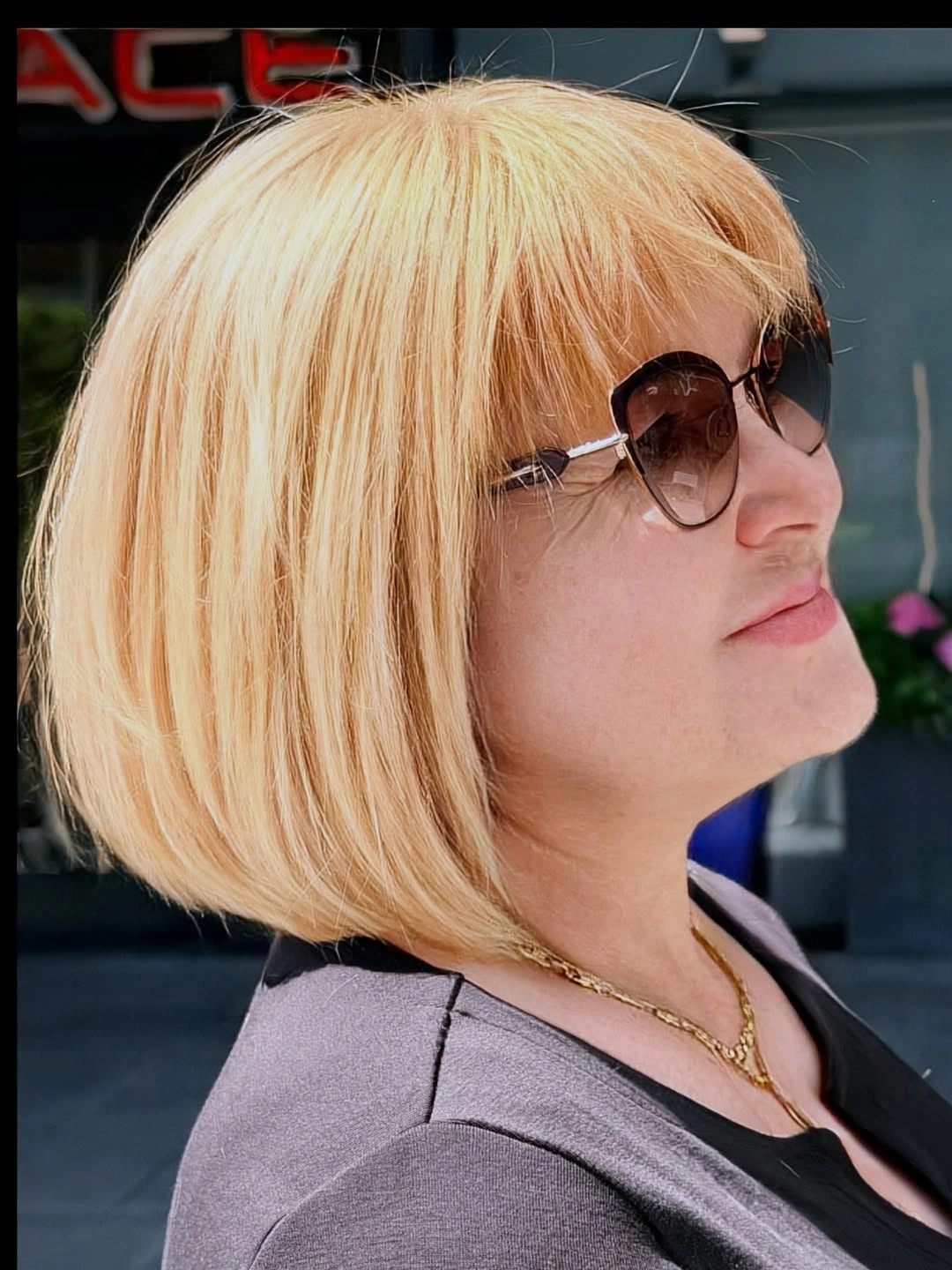 Blonde chin-length bob with full bangs and sunglasses