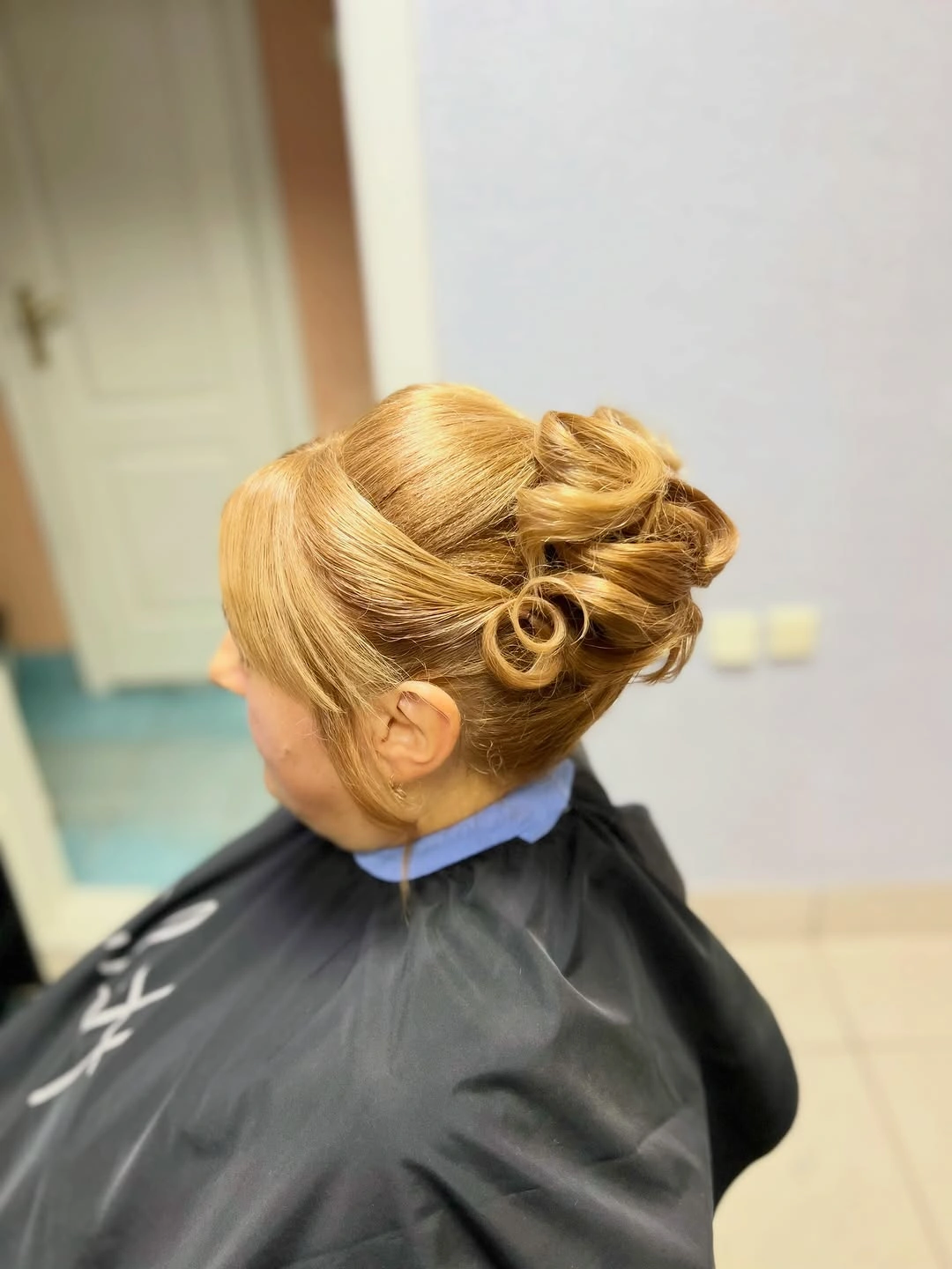 Blonde looped updo with smooth side sweep and rolled back