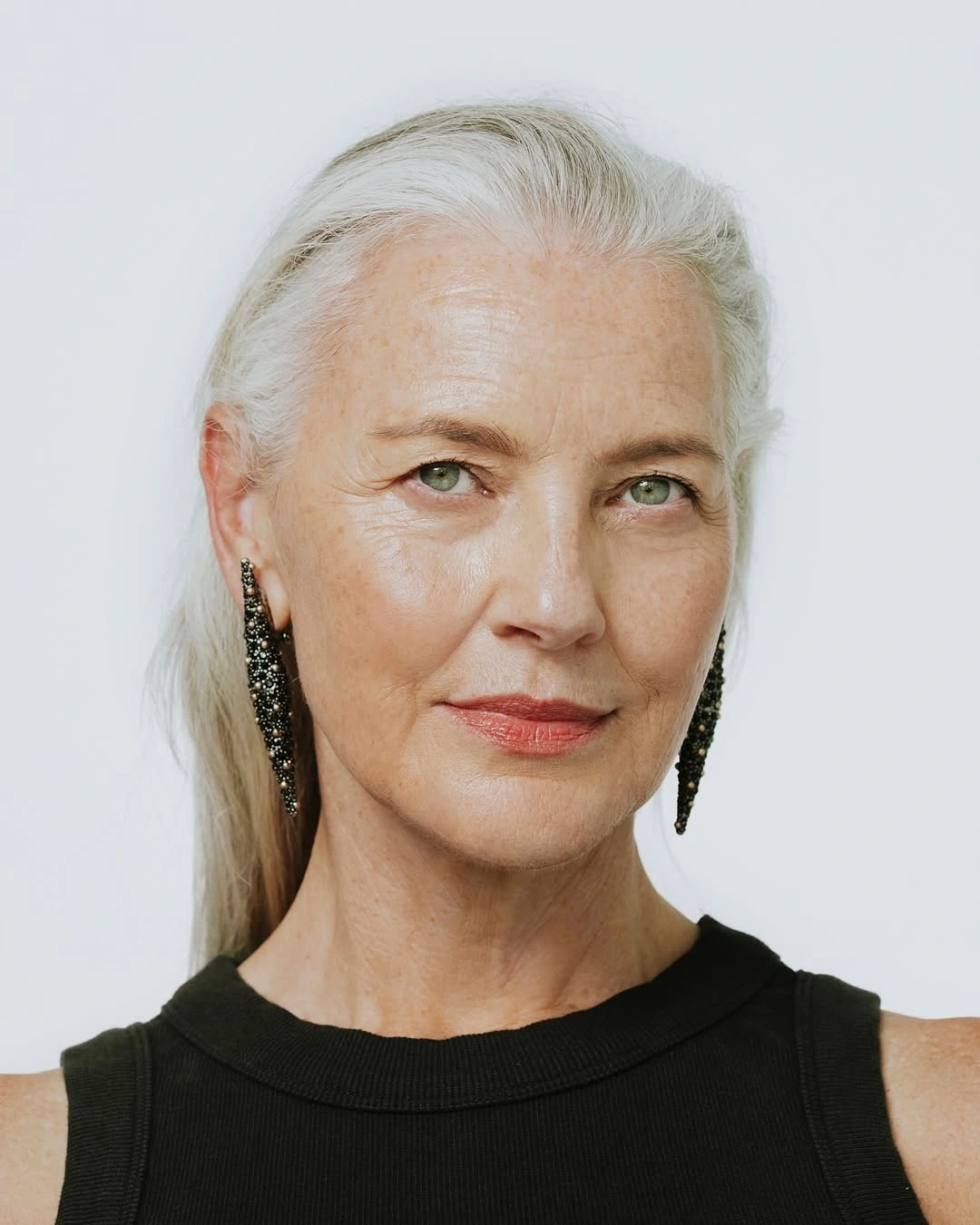 Long silver hair drawn back with exposed ears and earrings