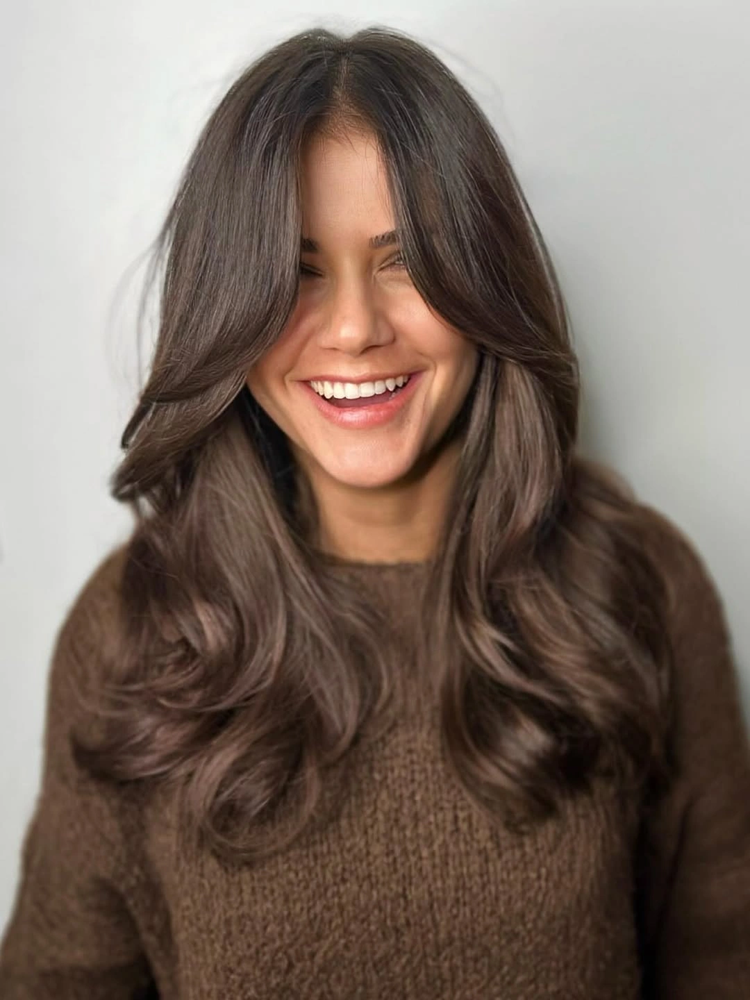 Long brunette layered hair with center part and rounded waves