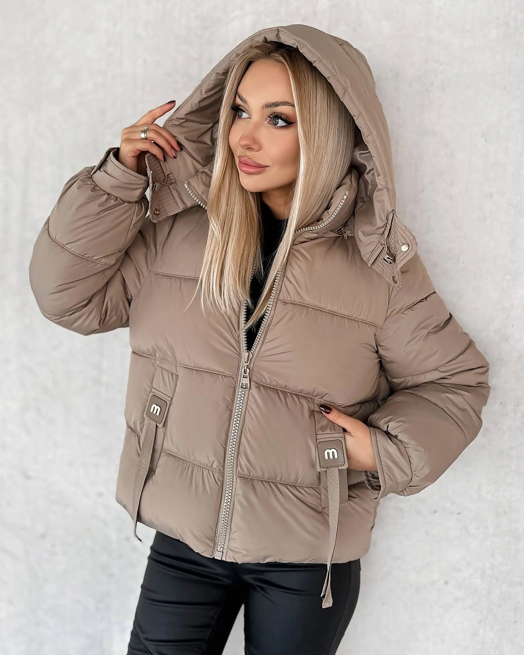 Beige hooded puffer-style jacket over black outfit