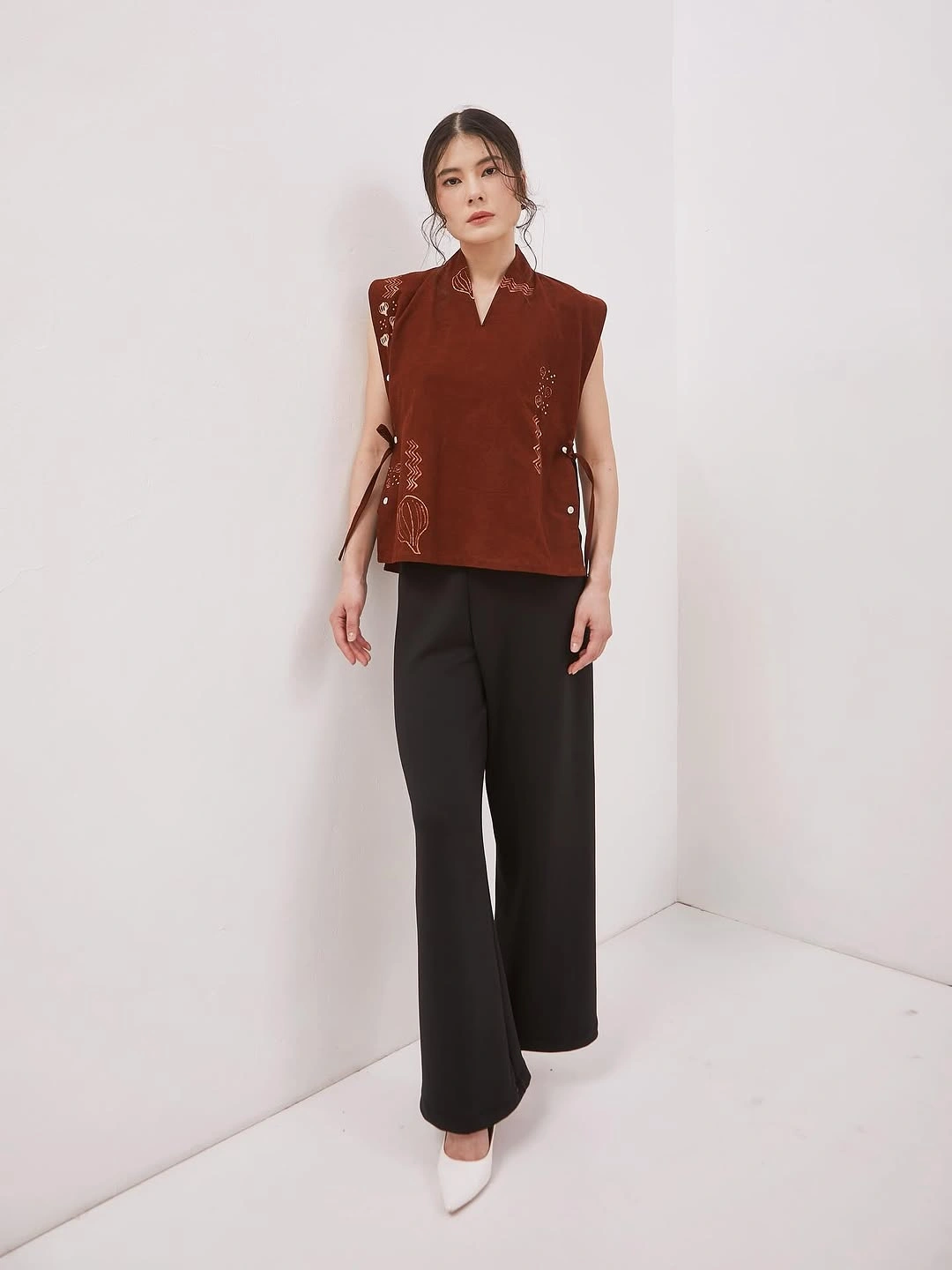 Rust sleeveless embroidered top with black cropped trousers
