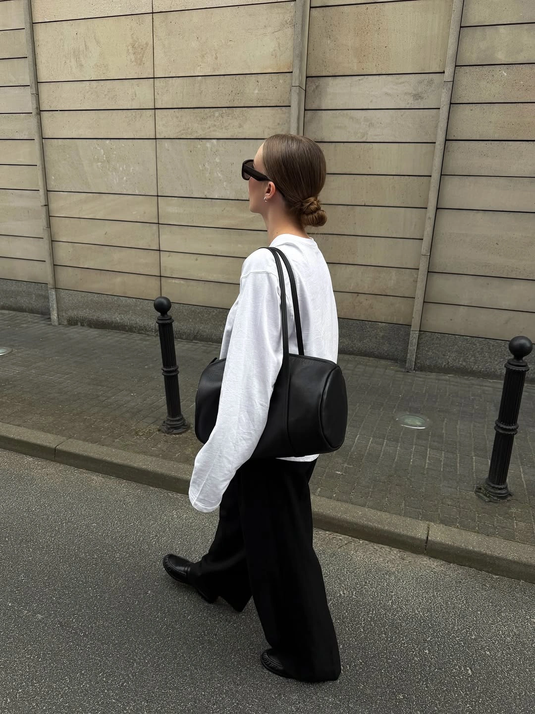 White long-sleeve top with black wide trousers and shoulder bag