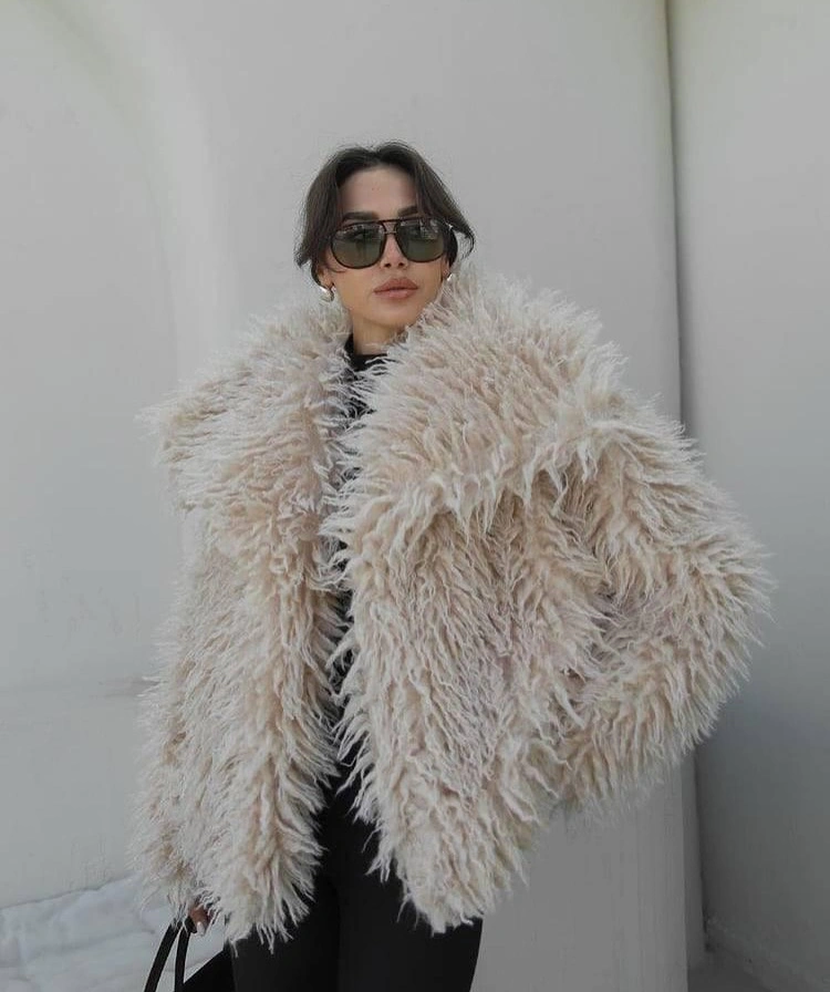 Cream shaggy jacket over dark clothing with sunglasses
