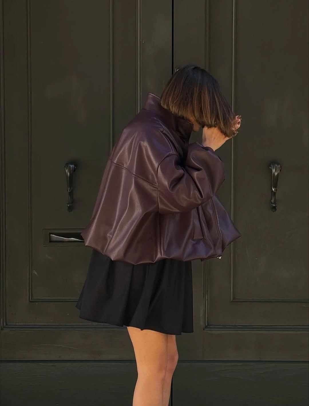 Oversized glossy brown jacket with short black skirt