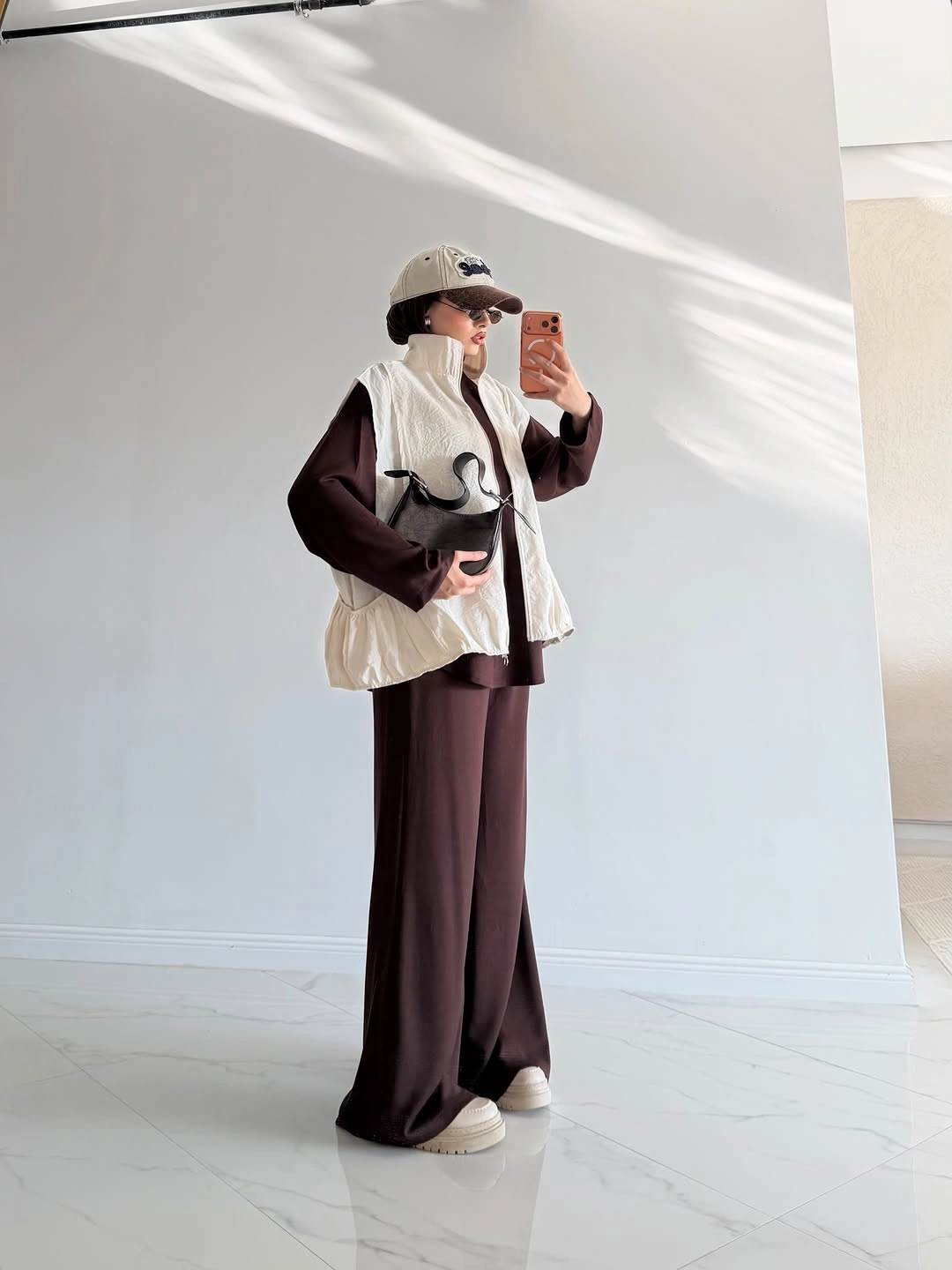 Cream quilted vest, dark brown separates, cap and sneakers