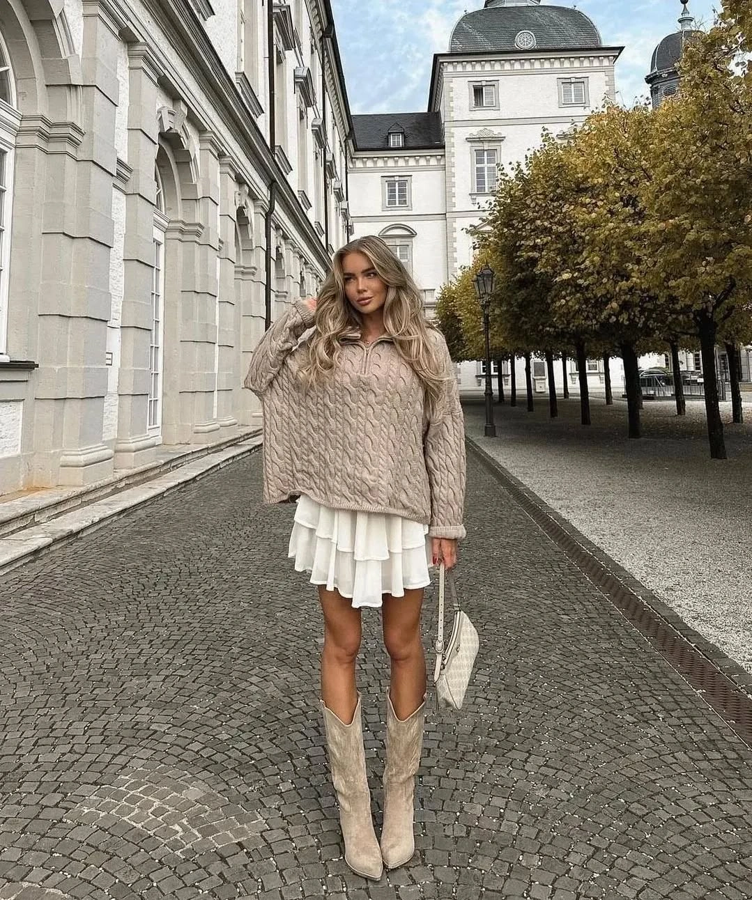 Taupe cable-knit sweater, white tiered skirt and tall boots