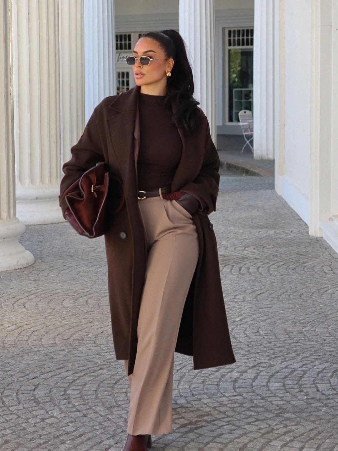 Dark brown coat, tan trousers, burgundy boots and bag