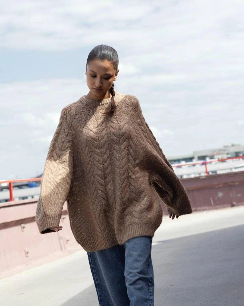 Oversized taupe cable sweater with blue jeans outdoors
