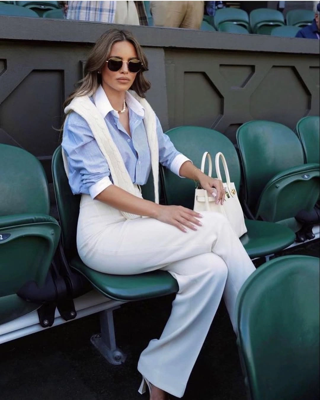 Pale blue shirt, white trousers, shoulder sweater and handbag