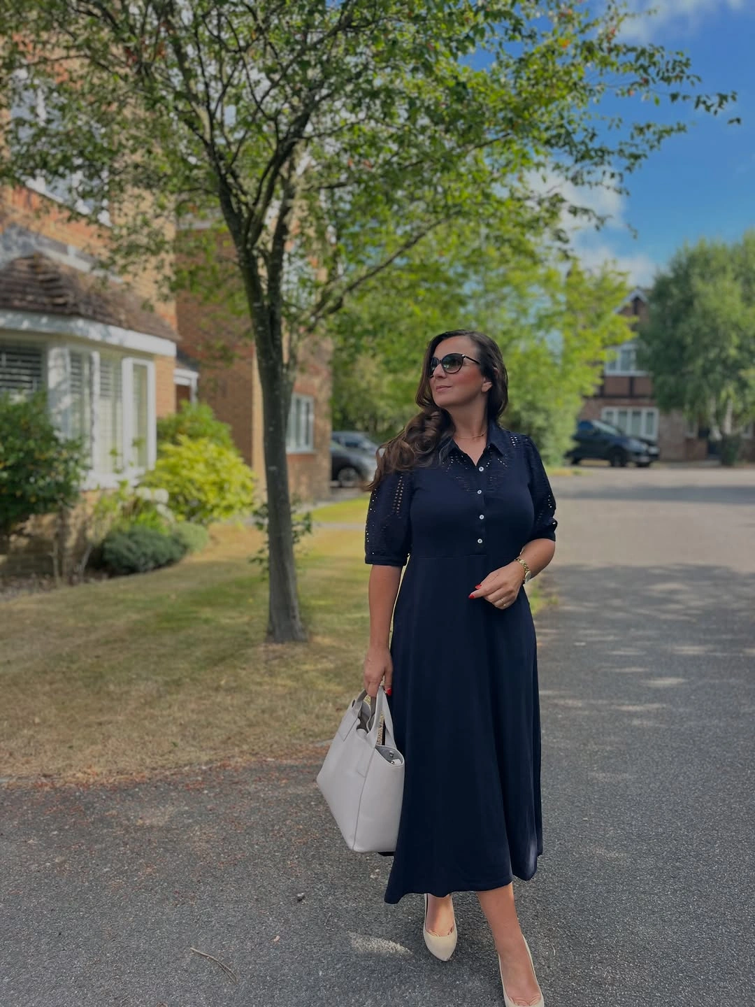 Dark button-front midi shirtdress with pale shoes and handbag