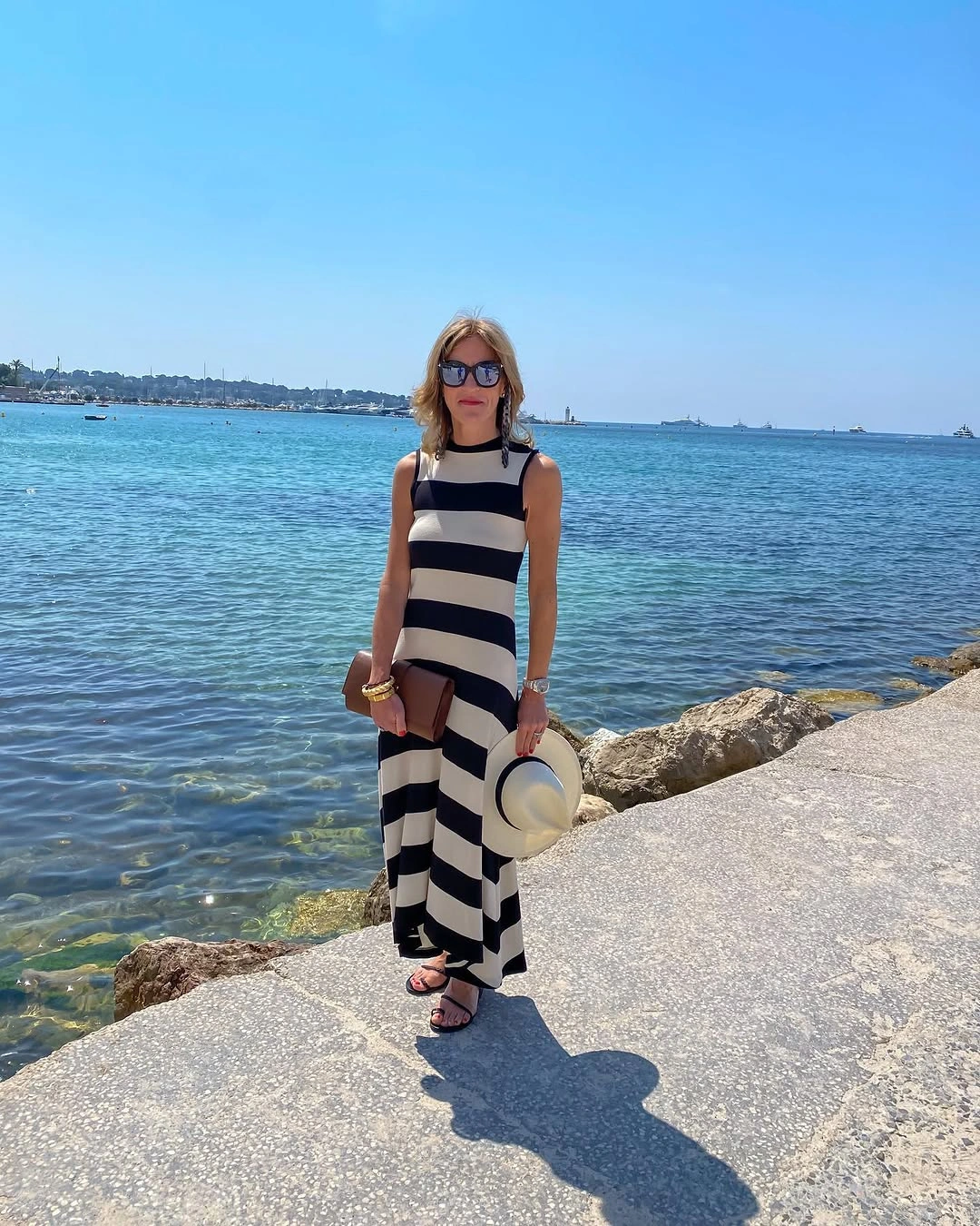 Sleeveless striped column with black sandals by the water