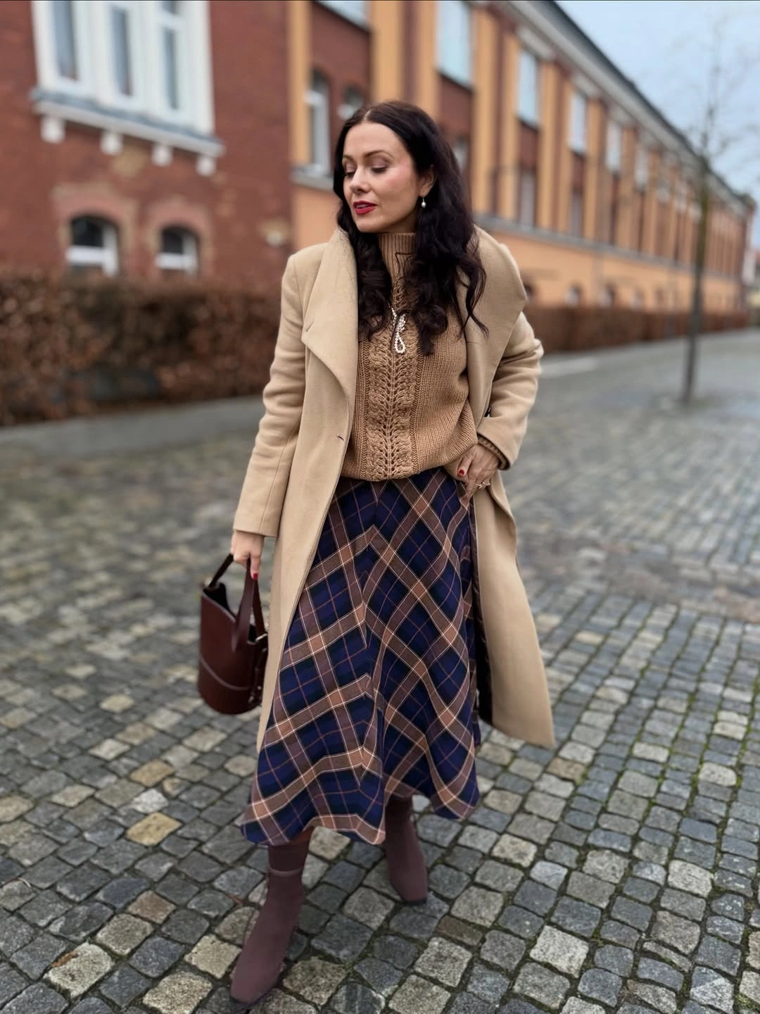 Camel coat over taupe knit and blue-brown plaid skirt