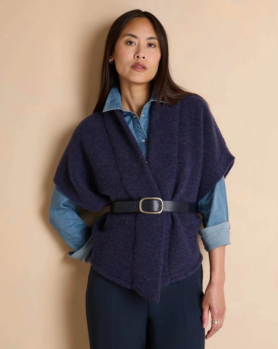 Dark draped layer belted over denim shirt and trousers