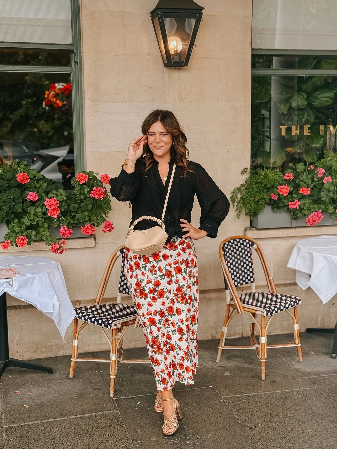 Black blouse with red floral skirt and beige crossbody bag
