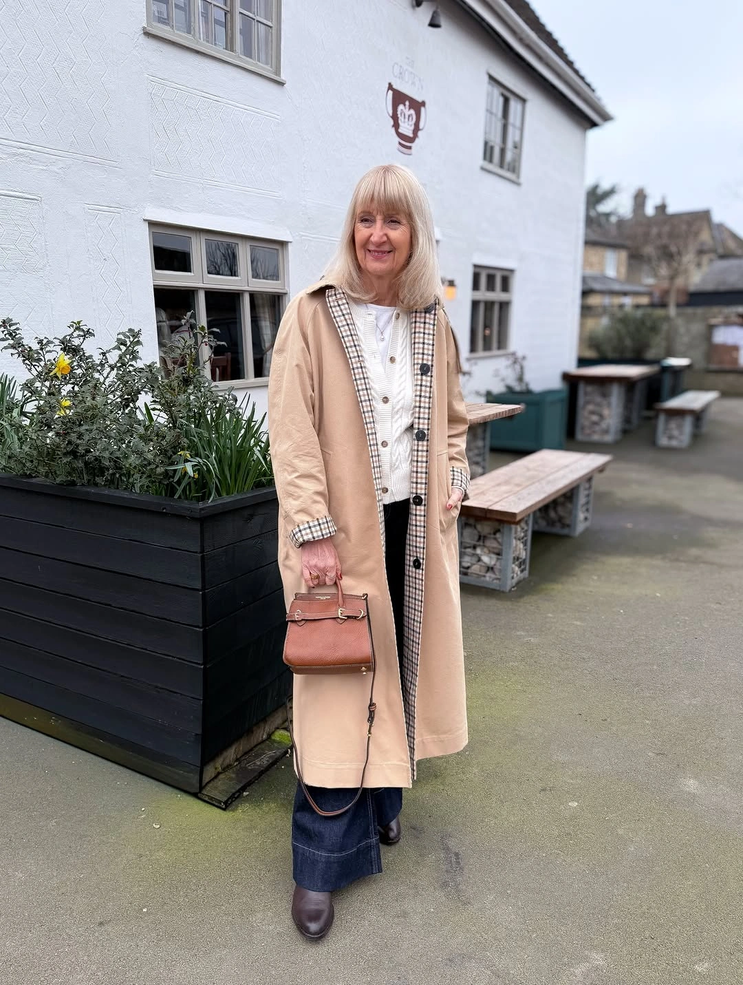 Beige long coat with checked detail and dark denim bottoms