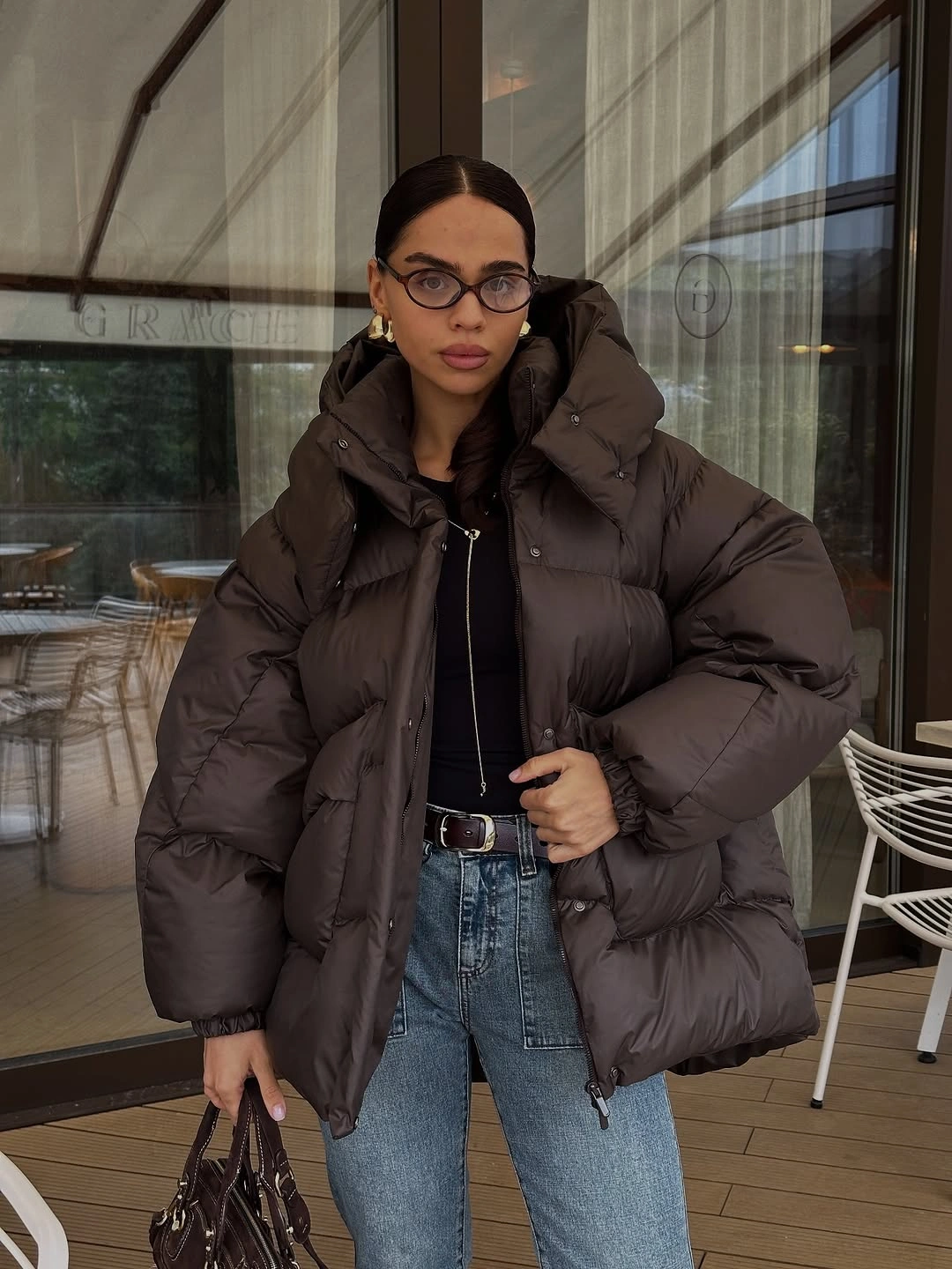 Dark brown oversized puffer over black top and blue jeans
