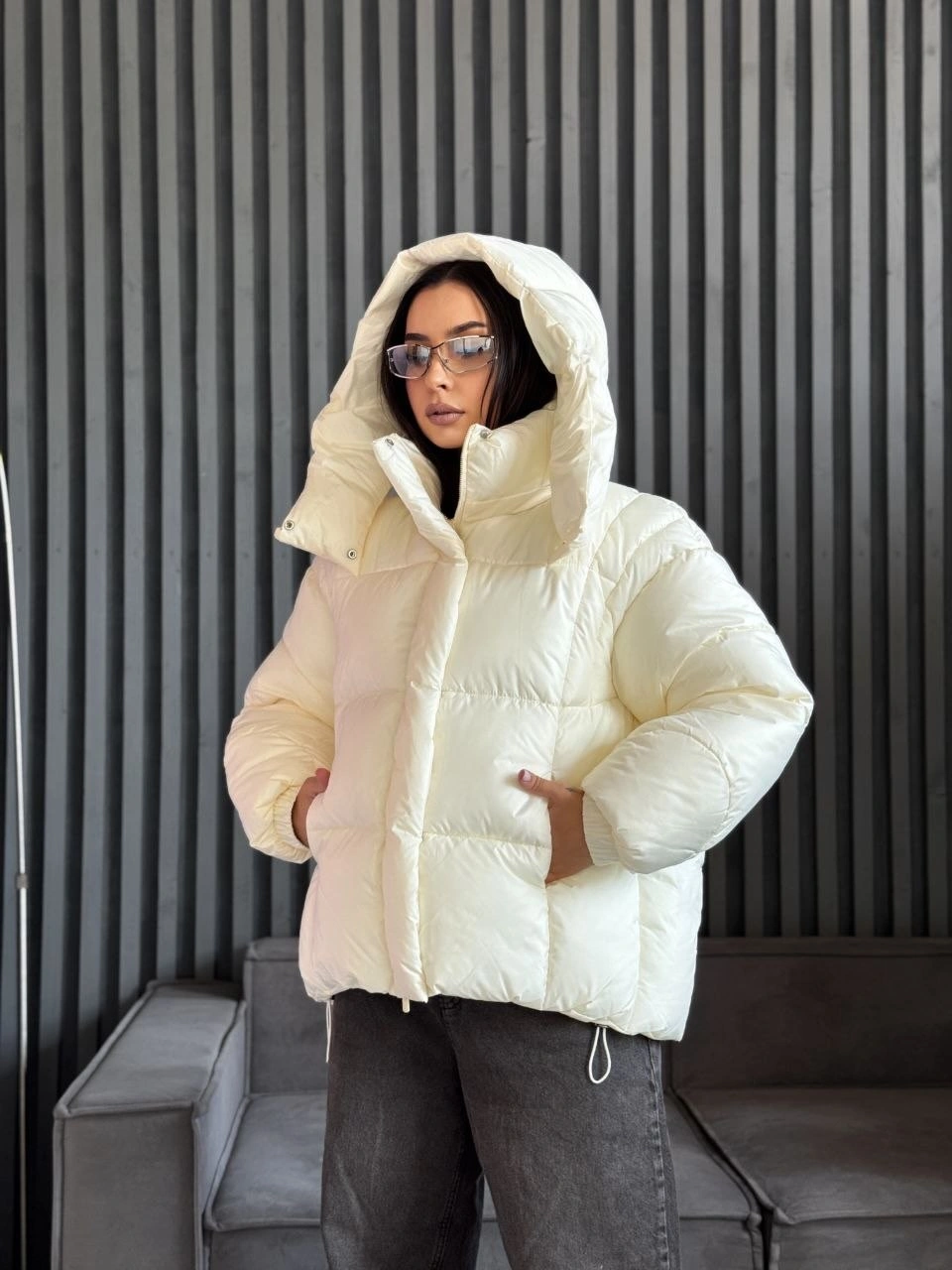 Cream hooded puffer with gray jeans and glasses