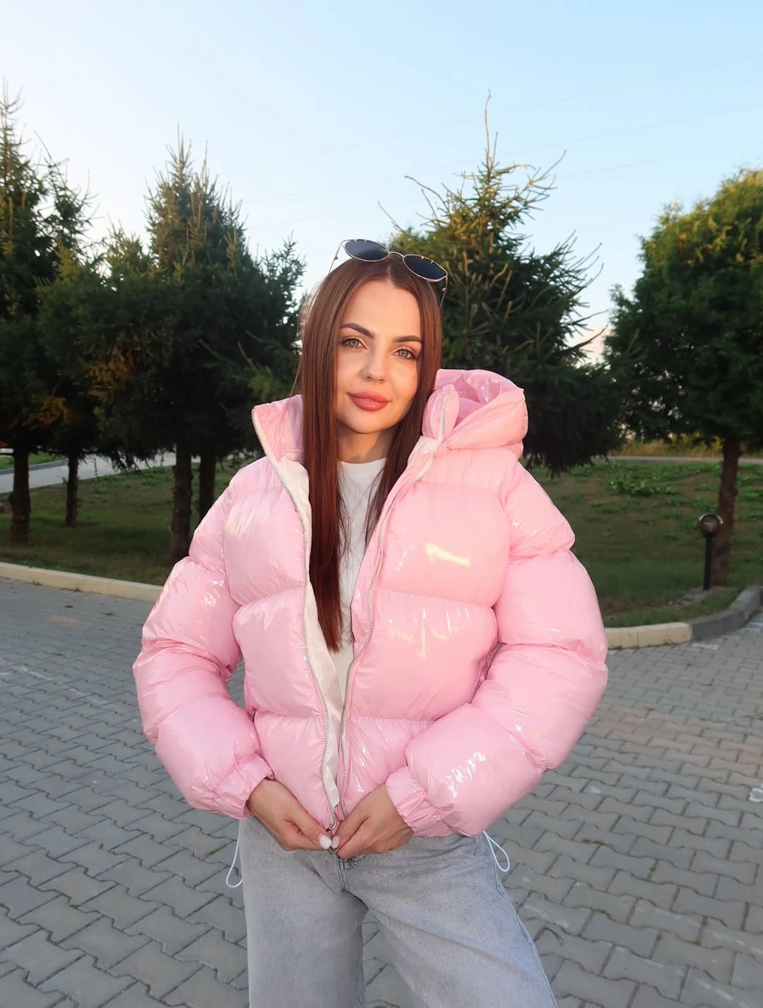 Pink hooded puffer with white top and pale gray jeans