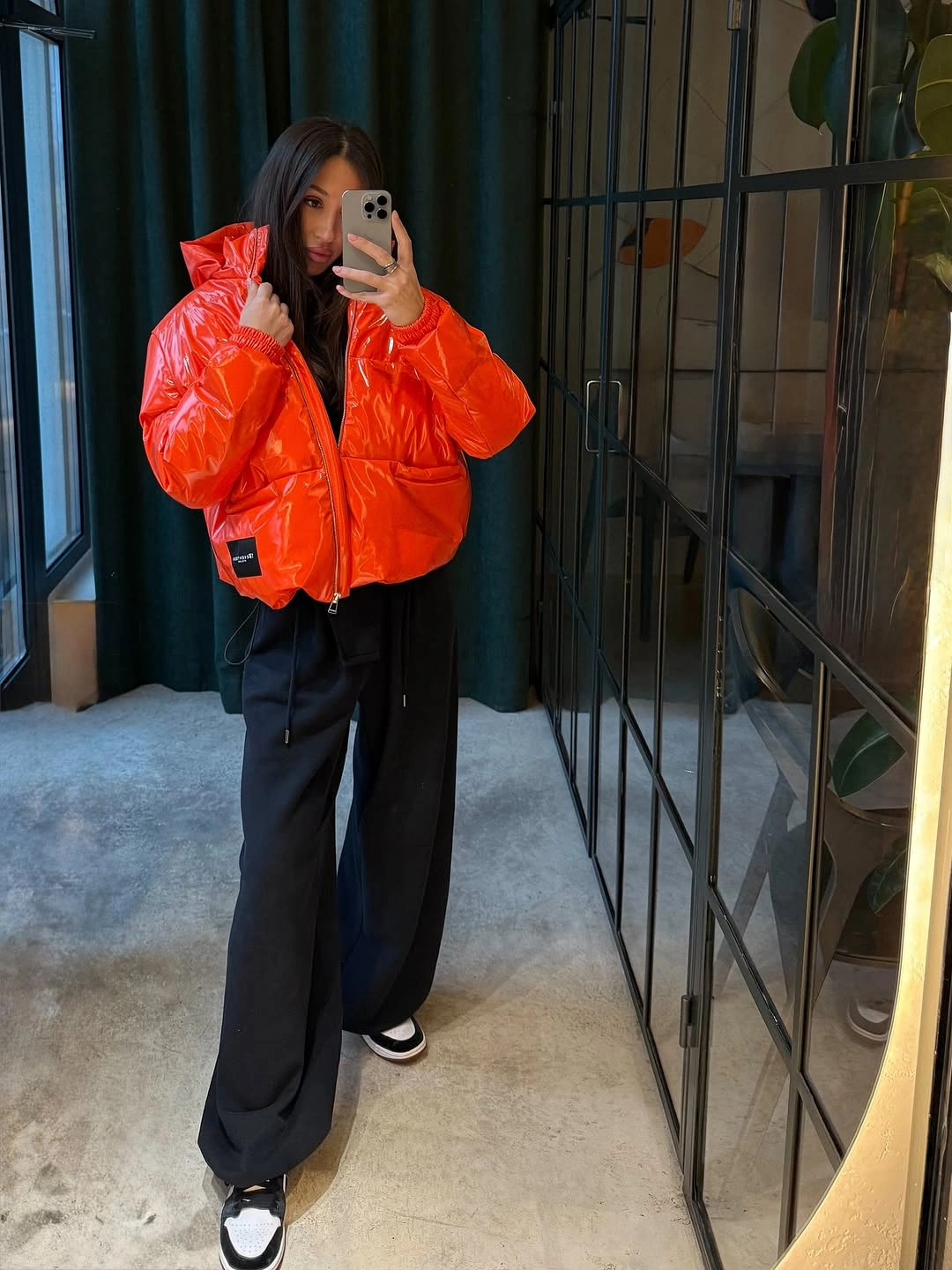 Bright orange cropped puffer with black wide trousers