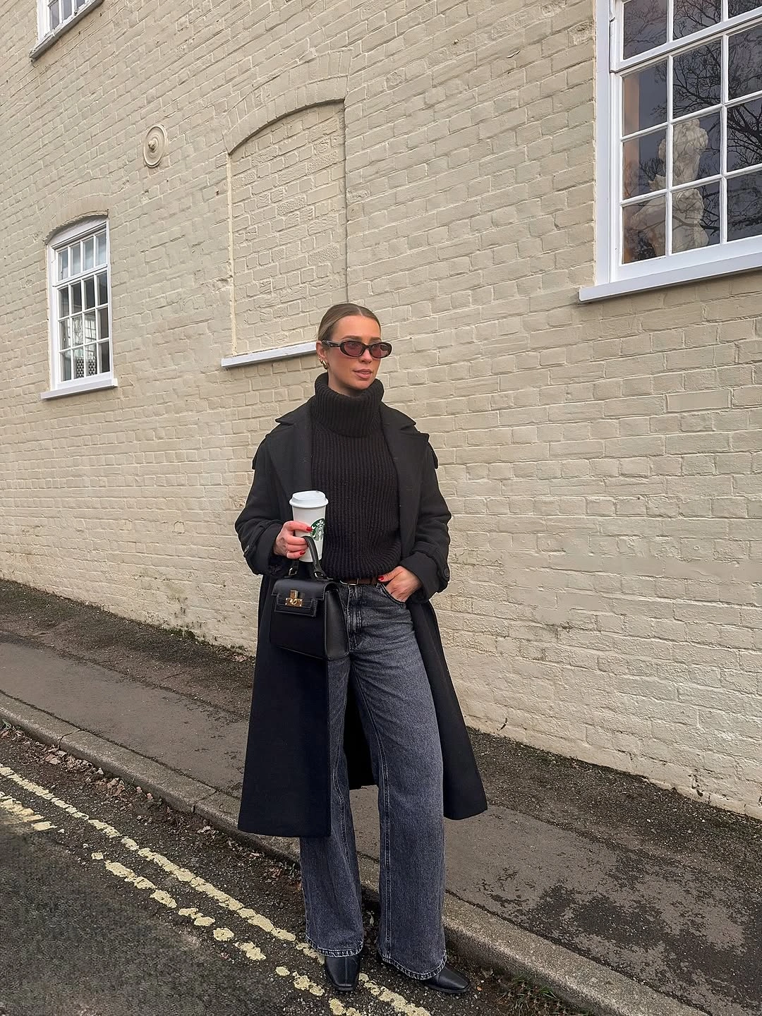 Dark coat and turtleneck with gray jeans and small bag