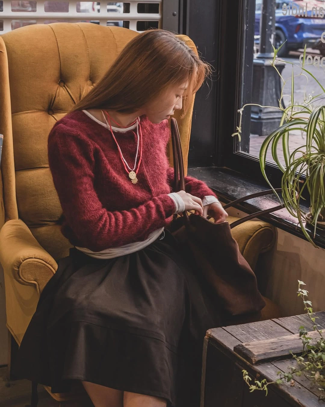 Red sweater with white underlayer, black skirt and pendant necklace
