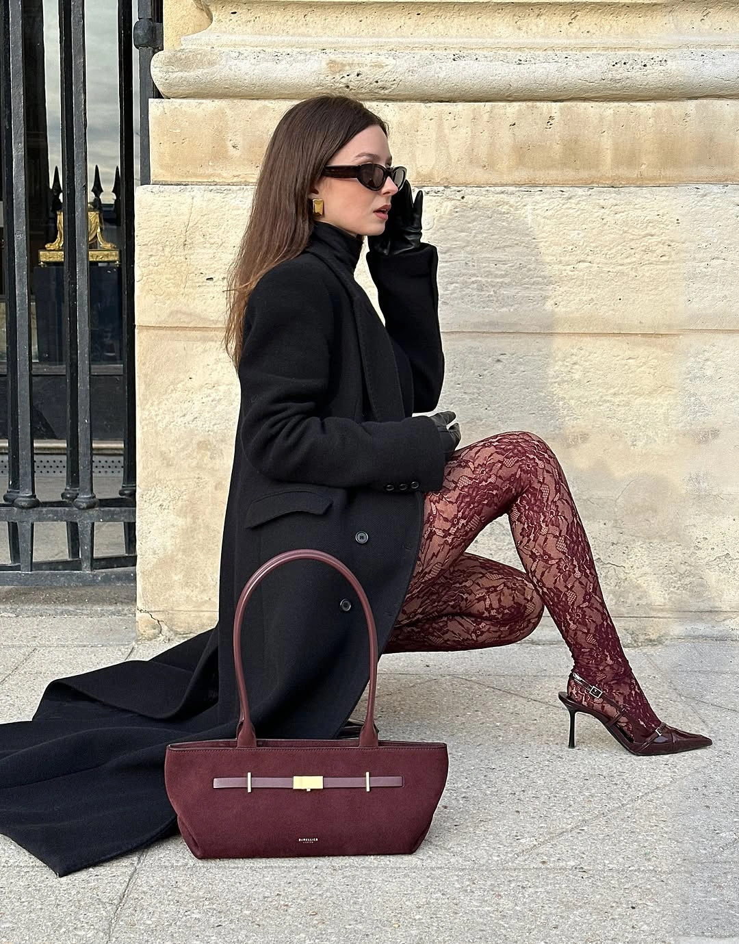 Black coat with burgundy patterned tights, heeled shoes and bag