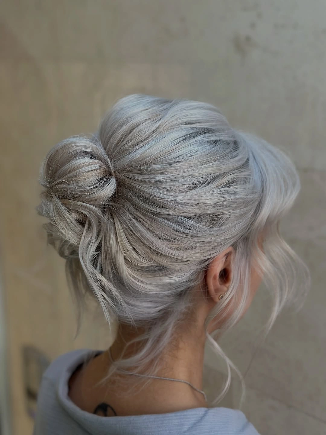 Low loose bun with pale silver grey white blonde hair