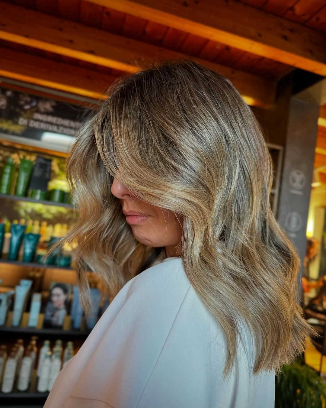 Shoulder-length beige and honey waves with darker roots and a side-swept front