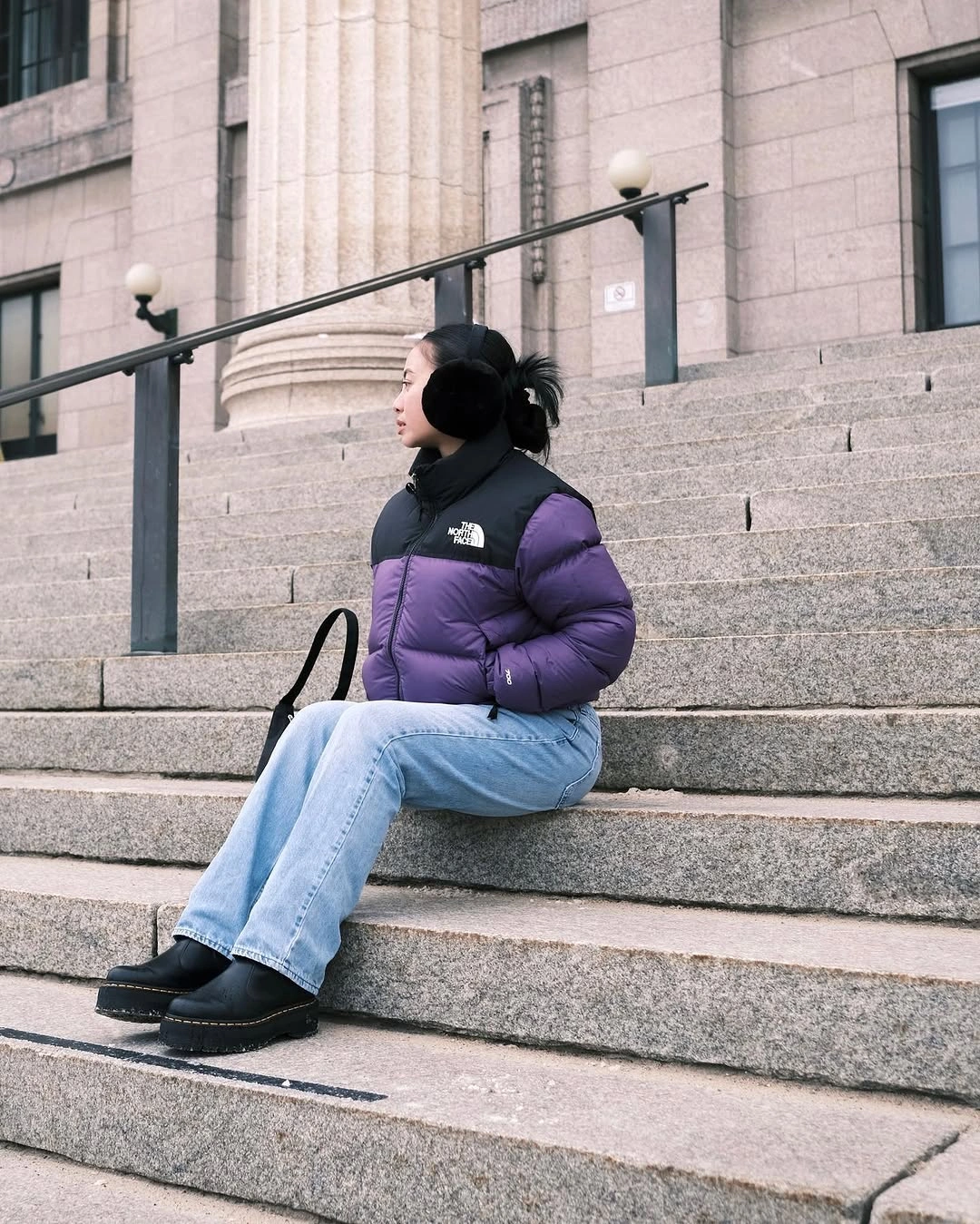 Purple puffer with pale blue jeans and black footwear
