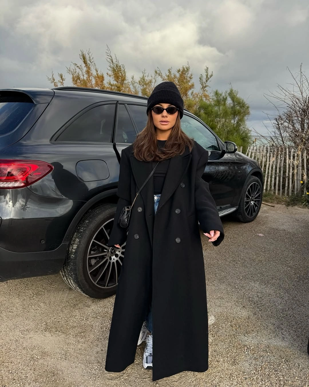 Long black coat with beanie, sunglasses and denim glimpse