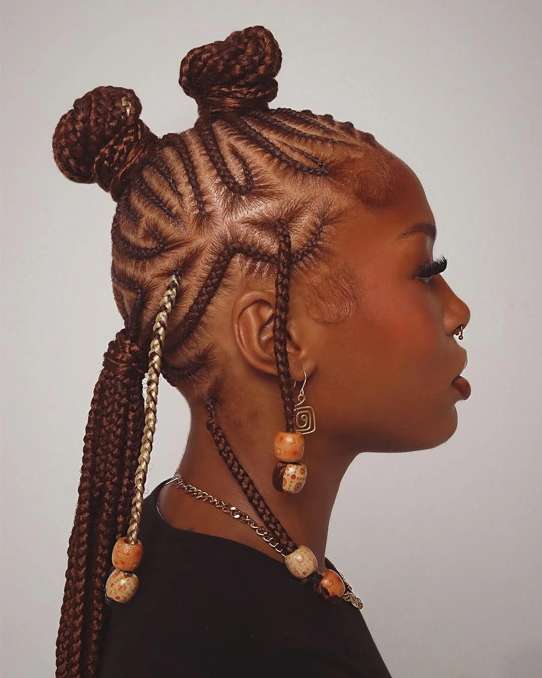 Side profile with cornrows rounded buns dark braids and beads