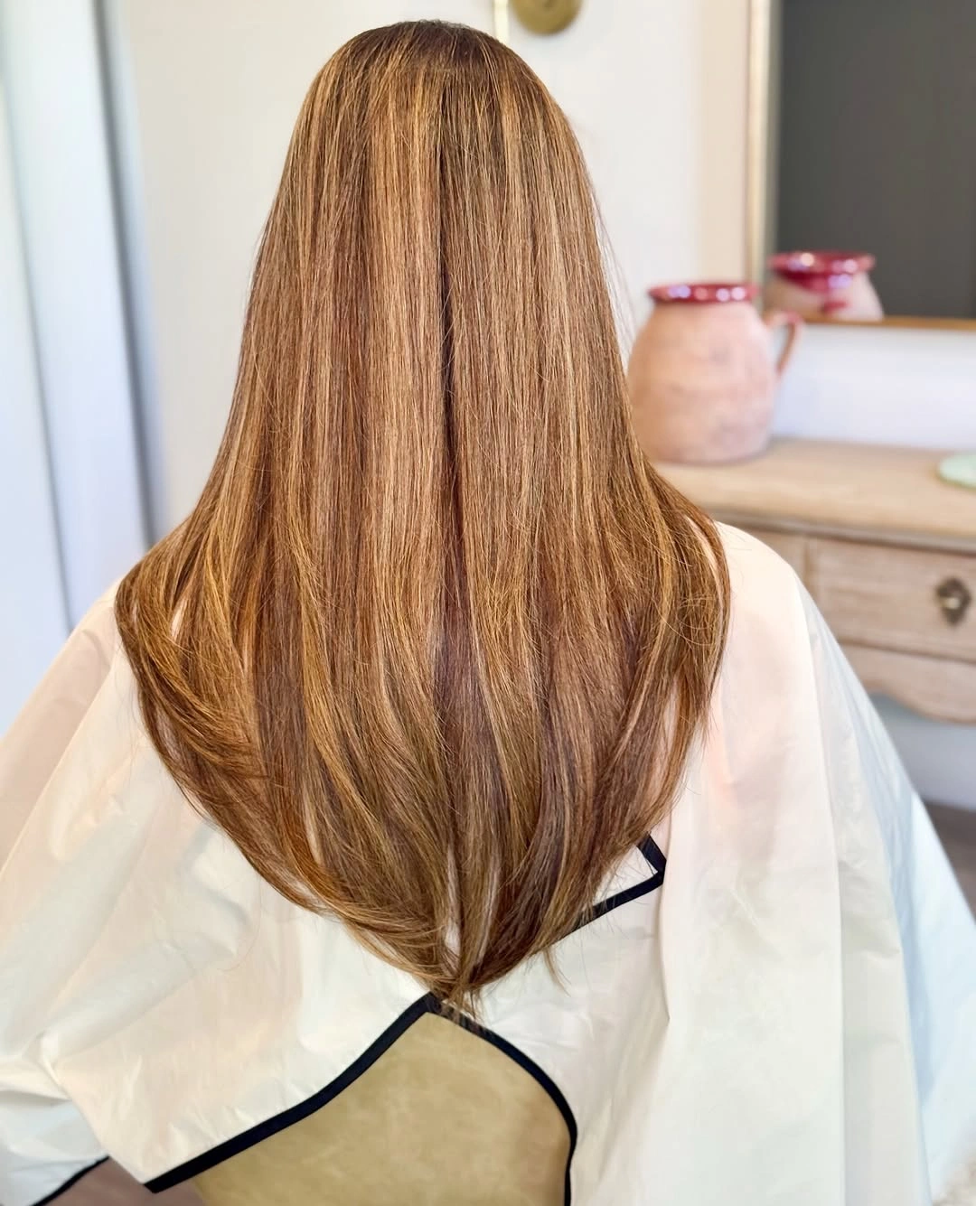 Long warm brown layered haircut shown from the back