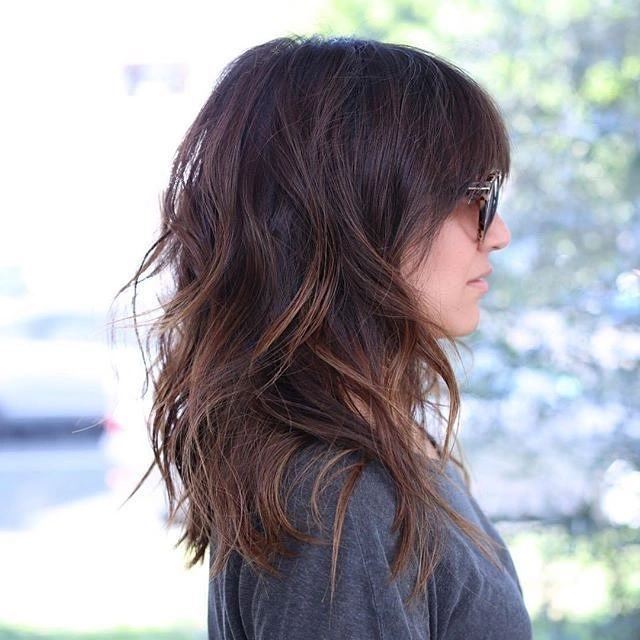 Wavy brunette mid length haircut shown from the side