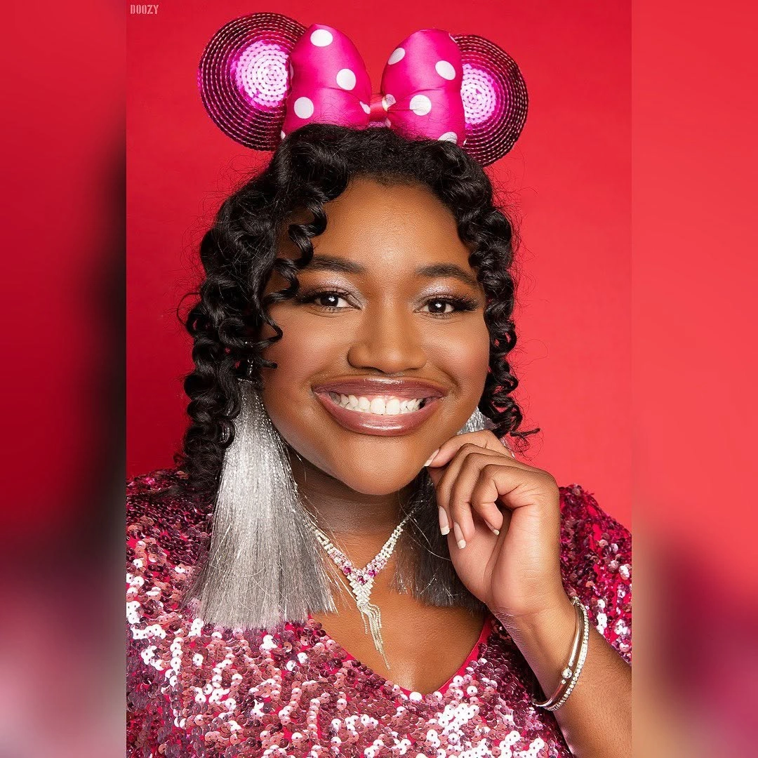 Defined dark curls with bow headband and bright red background