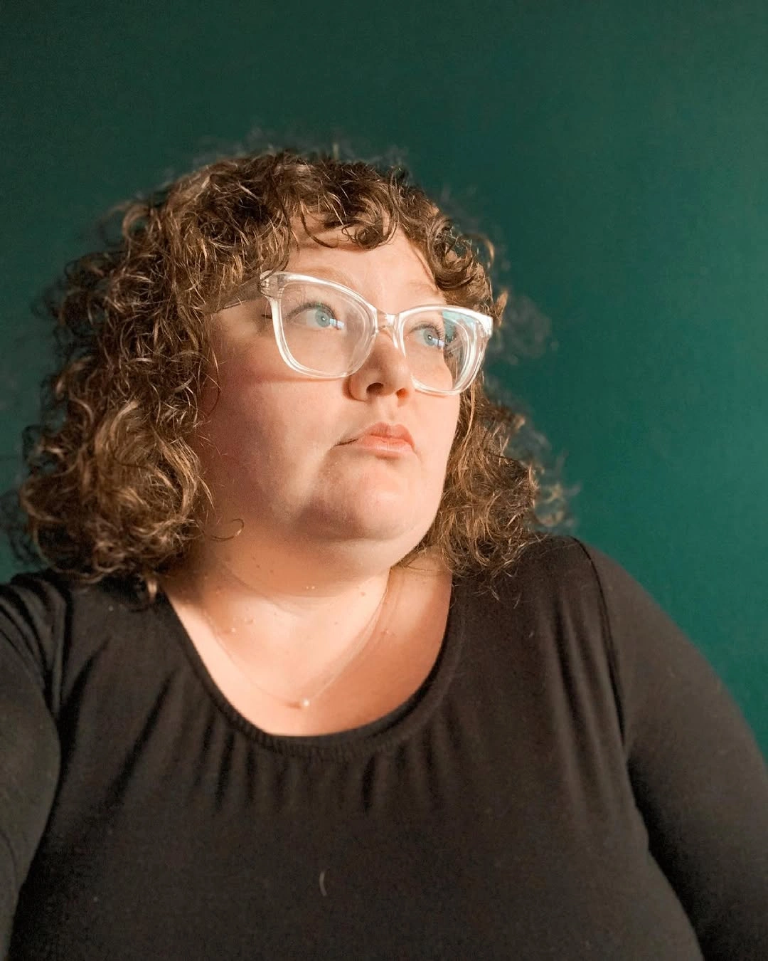 Curly shoulder-length bob with clear glasses and rounded sides
