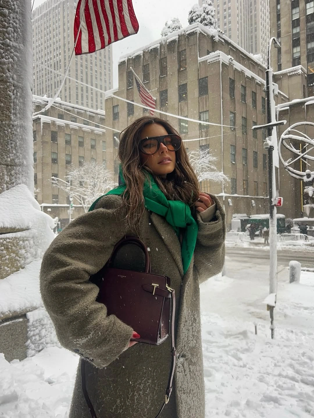 Person in gray coat and green scarf on snowy street