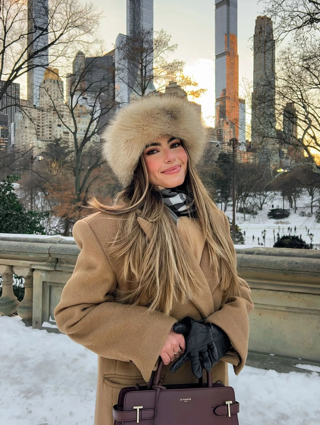 Person in camel coat, pale fur-like hat and gloves