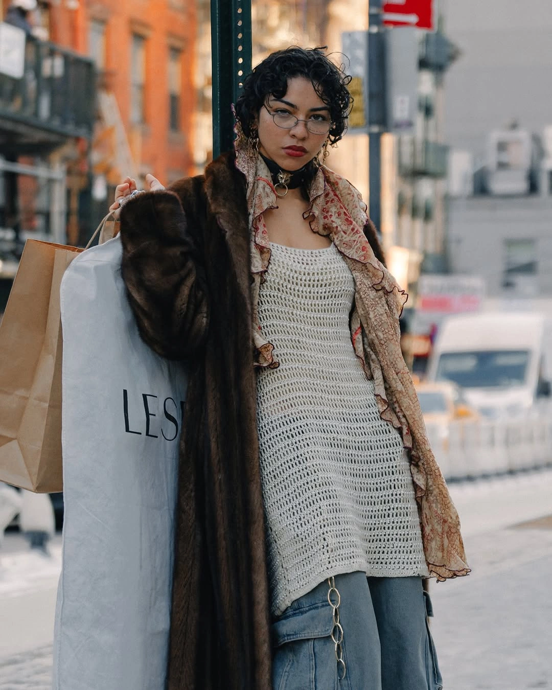 Person in gray textured long layer with jeans and shopping bags