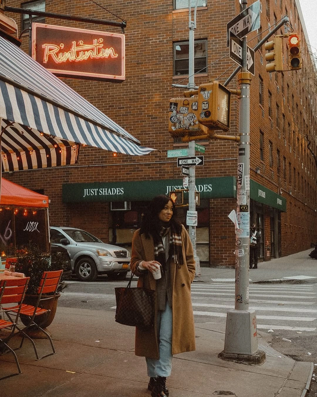 Person in camel coat, striped scarf and pale jeans outdoors