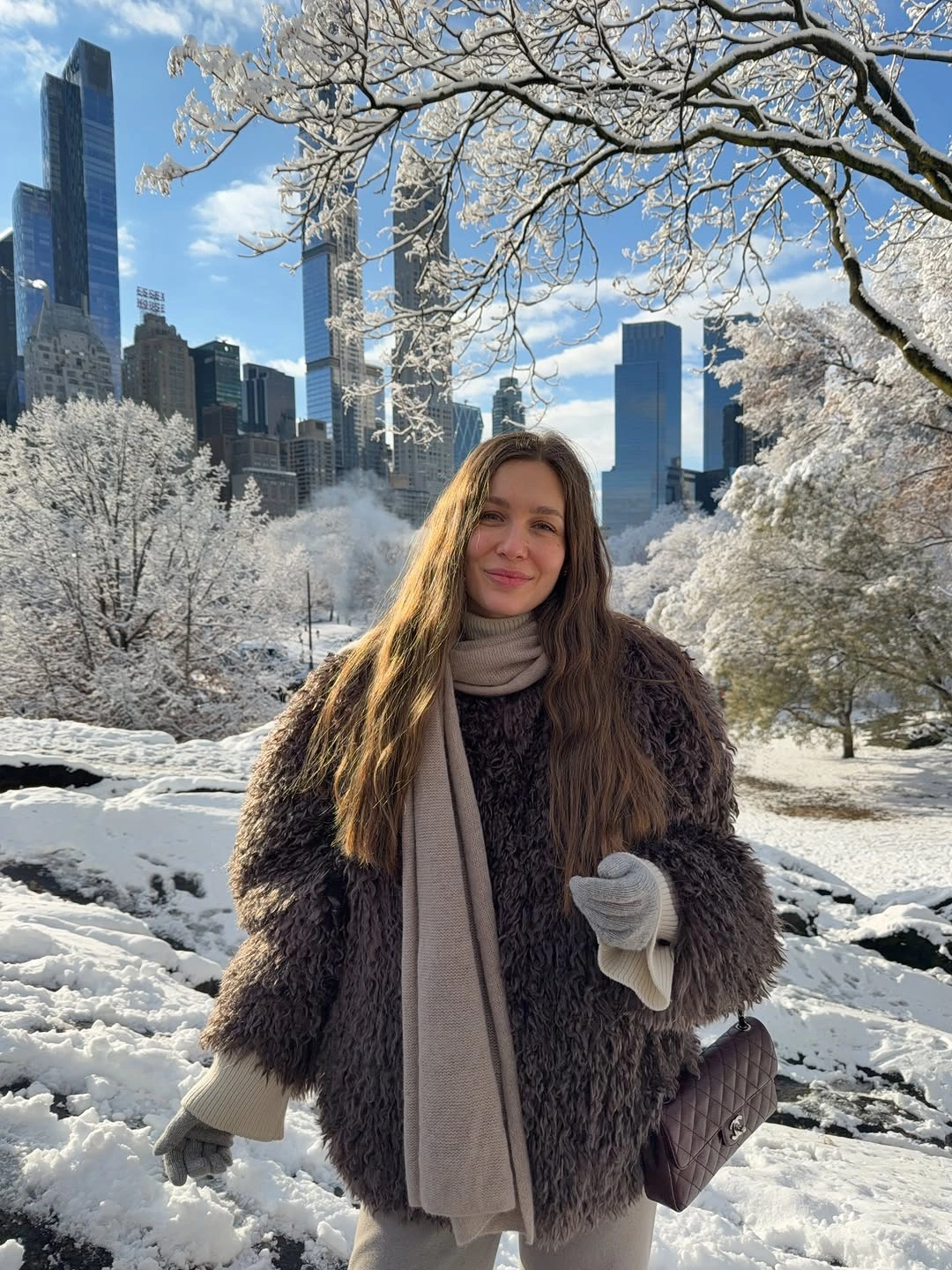 Person in dark shag-textured coat with pale scarf in snowy park