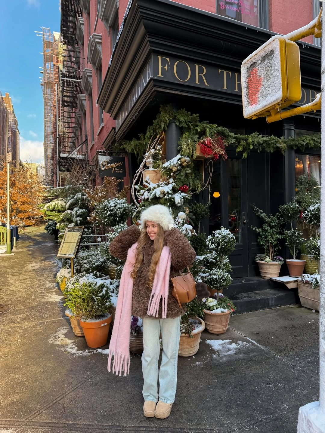 Person in brown textured jacket, pink scarf and pale jeans