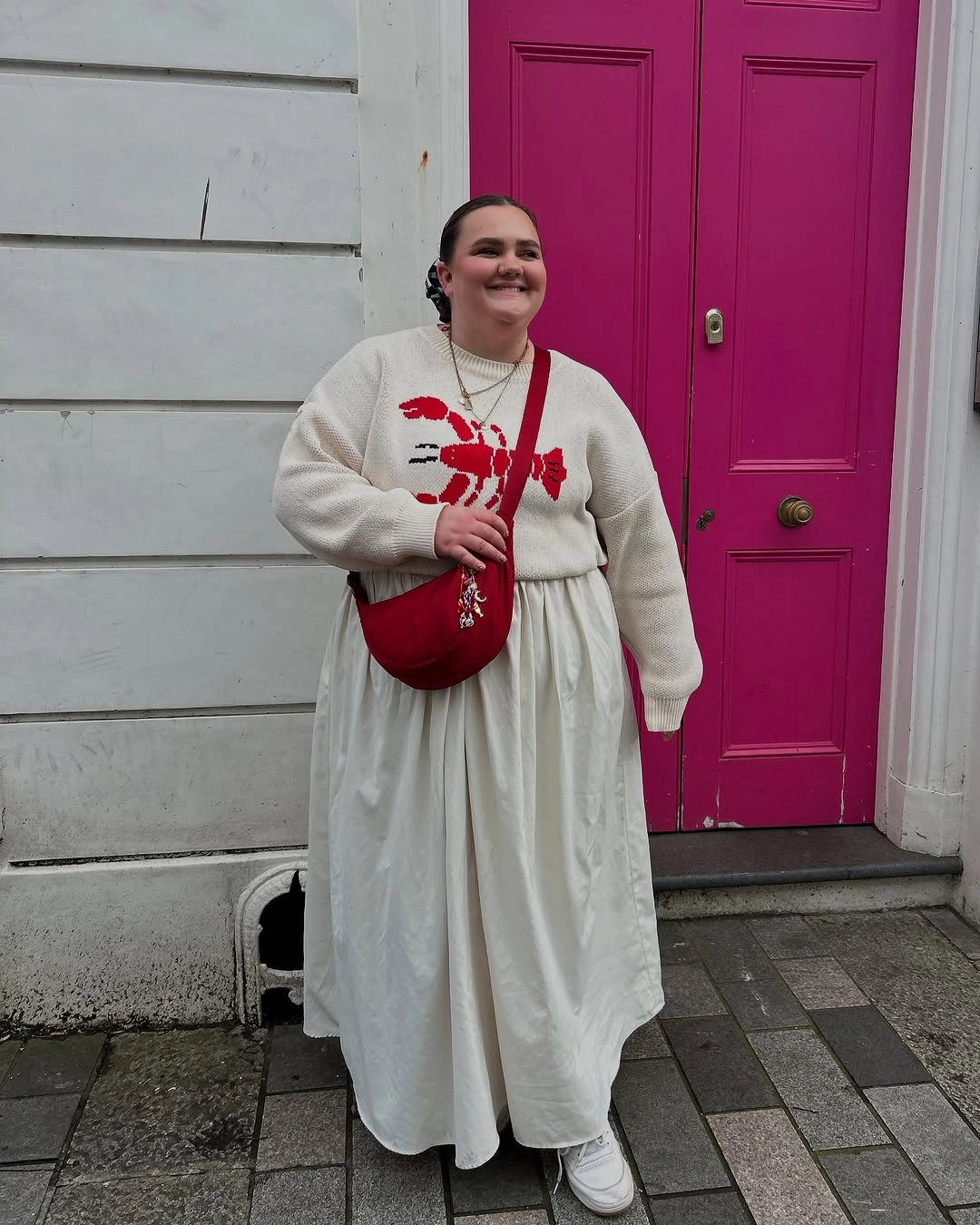 Cream sweater and skirt with red bag and graphic
