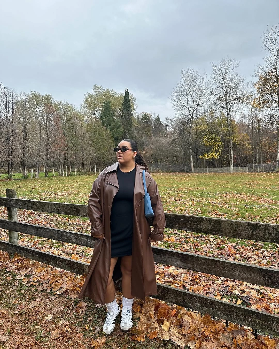 Brown leather-like coat over black outfit with white sneakers