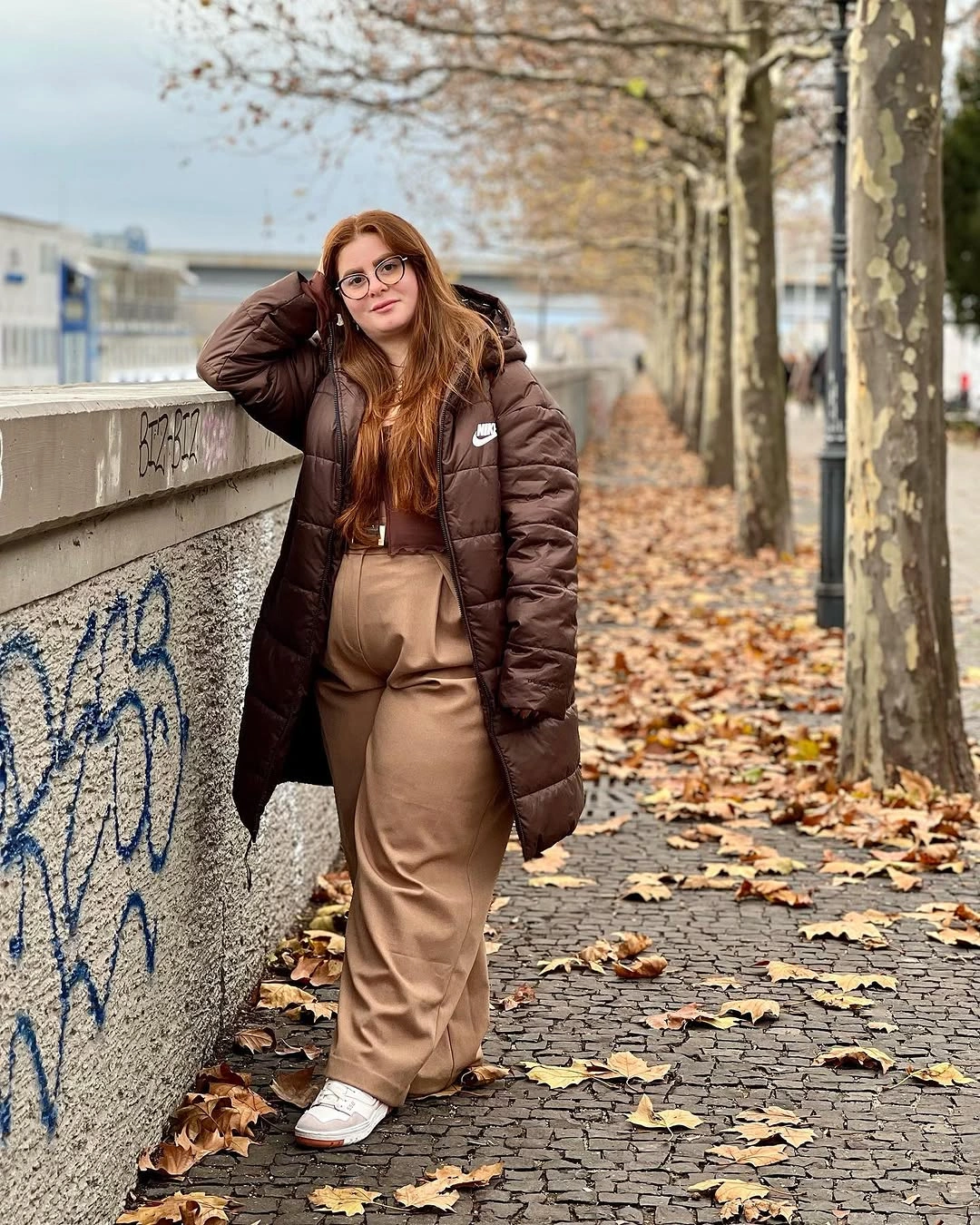 Long brown puffer with tan wide trousers and sneakers