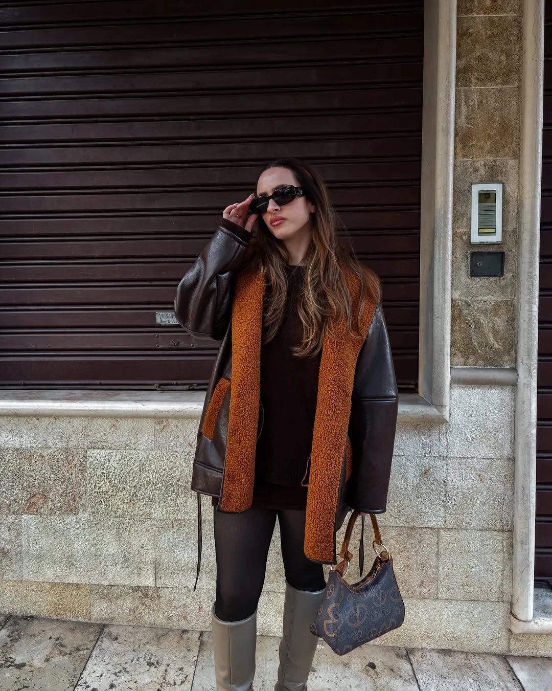 Brown leather-look jacket with rust trim and gray boots