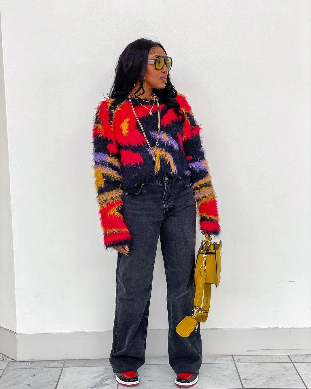 Multicolor striped sweater with black jeans and yellow handbag
